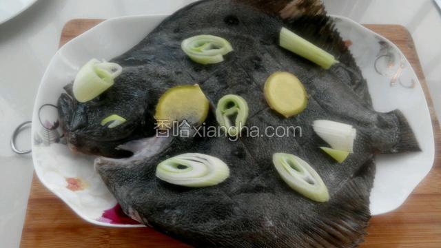把料酒和盐混合后均匀涂抹在鱼身上，放上葱花和姜片。