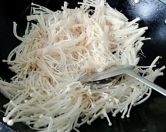 锅再次放入2勺子花生油，等油温热后倒入金针菇翻炒