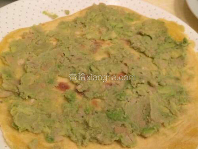 取一片薄饼，抹上牛油果豆蓉酱；
