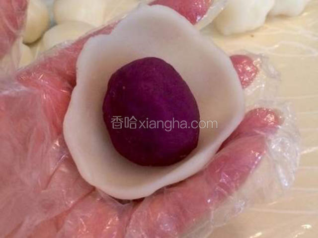 取一份冰皮面团捏成面皮，包入紫薯馅儿(紫薯馅每份25克)，搓圆；