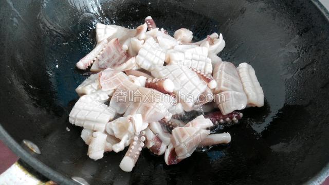 锅中倒油烧热后放入鱿鱼翻炒。