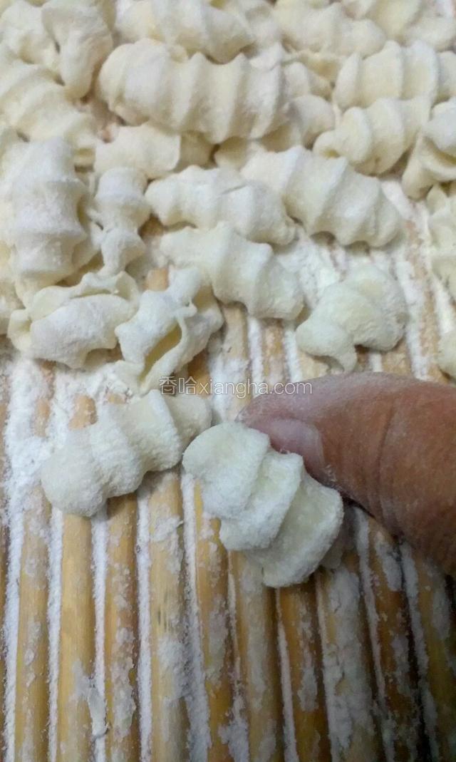 在有花纹的盖帘上用拇指搓成麻食