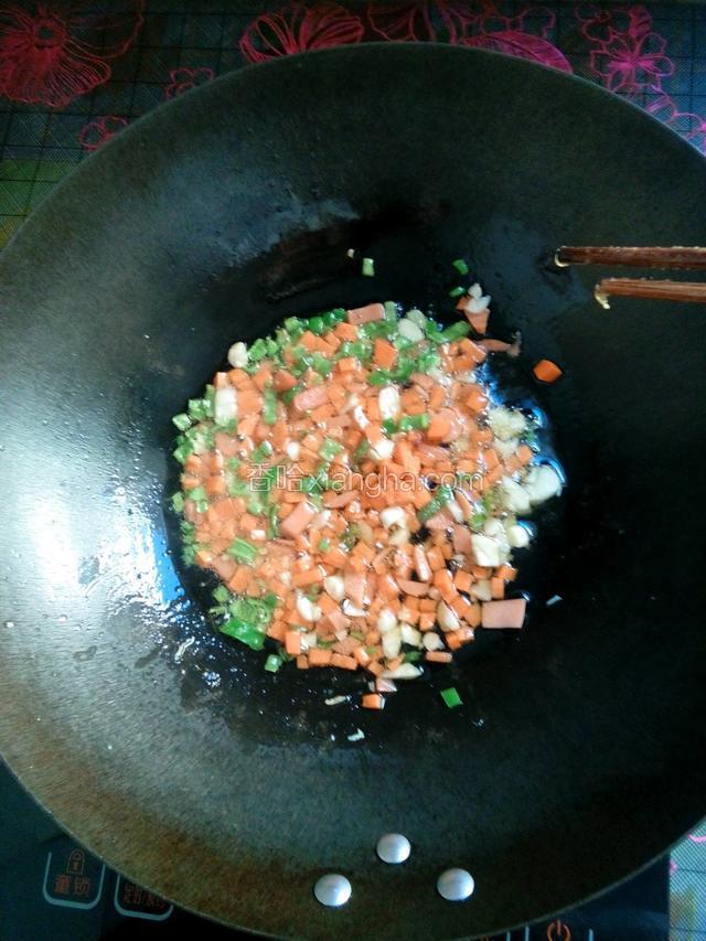 锅里再添油倒入刚才切好的辣椒胡萝卜，香肠和蒜瓣炒两分钟加一点盐进去