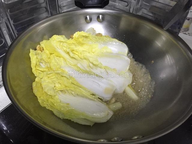 半分钟后加入一碗水，白菜的茎部比较难熟，先泡在水里煮一下，叶子部分暂时推到锅边不泡到水。
