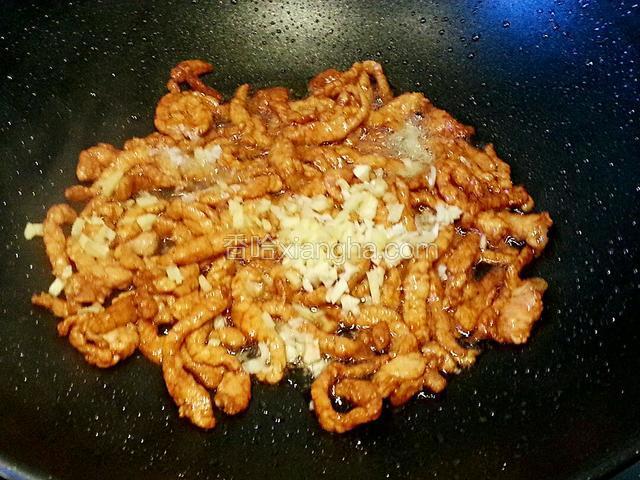 肉丝全部变色后延锅边淋入白酒，放姜蒜末翻炒均匀，盛出