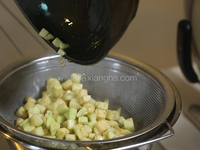 锅中烧热下油150克左右，大火烧至五六成热，把切好的茄丁放入油中，焯至六七成熟，变软后，倒入漏勺备用。