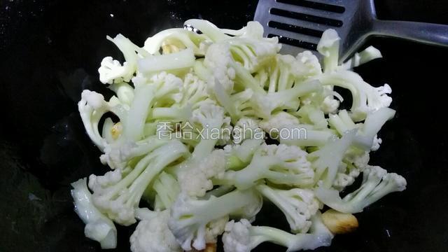 下菜花翻炒，先不要加水，多炒一会儿。看水分蒸发的差不多再加水，一定要少加，盖上锅盖焖熟。