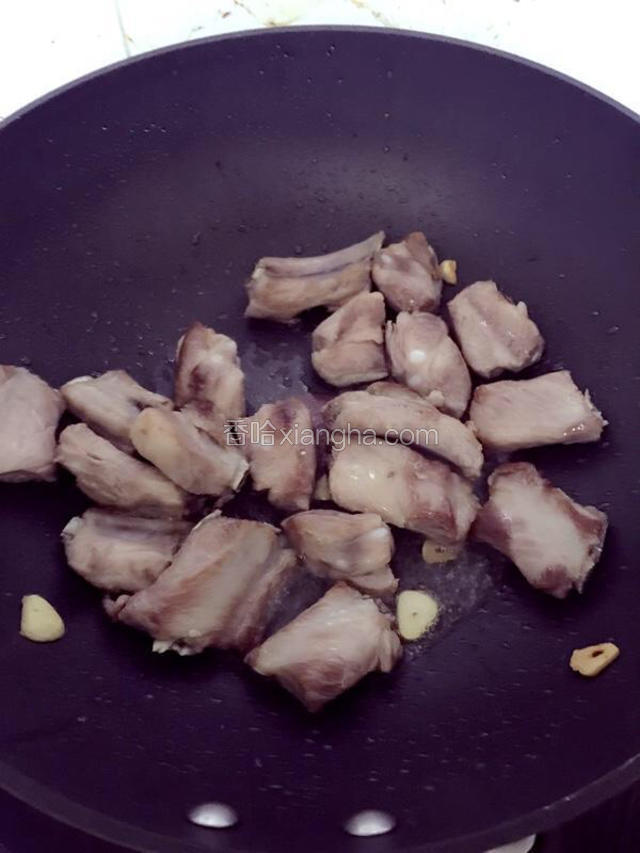 热锅下油，爆香蒜片，煎排骨至金黄。
