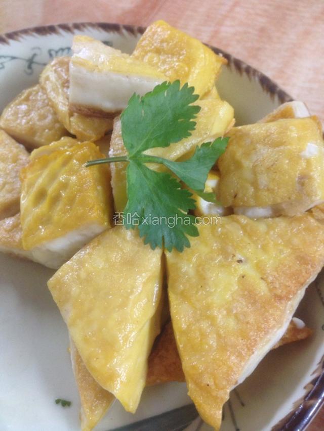 炸好的豆腐装盘，用香菜叶装饰。