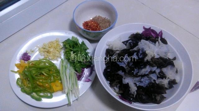 准备食材，木耳泡发洗净，辣椒和葱切丝，香菜切小段，蒜切成蒜末，辣椒面和芝麻放进小碗中。