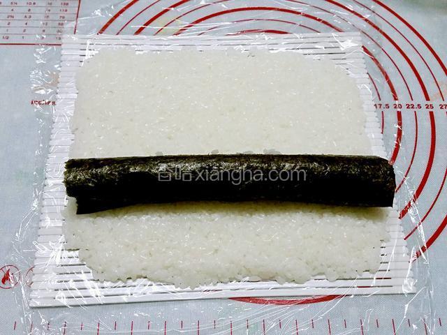 壽司席上放一块保鮮膜，在保鮮膜上均勻的放上米飯，再放上已卷好的饀料