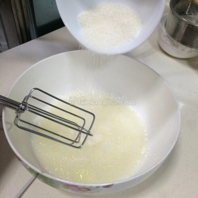 用电动打蛋器低速打至起粗泡，一次加入全部的粗砂糖