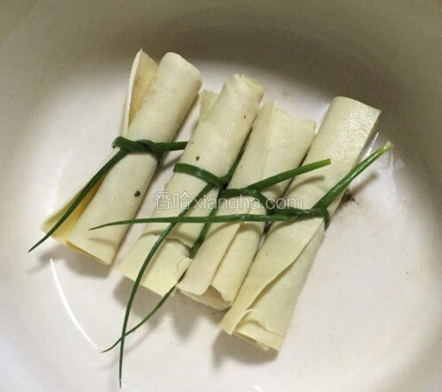 在收尾处涂上鸡蛋白，再用开水烫过的小葱将肉卷扎好即可