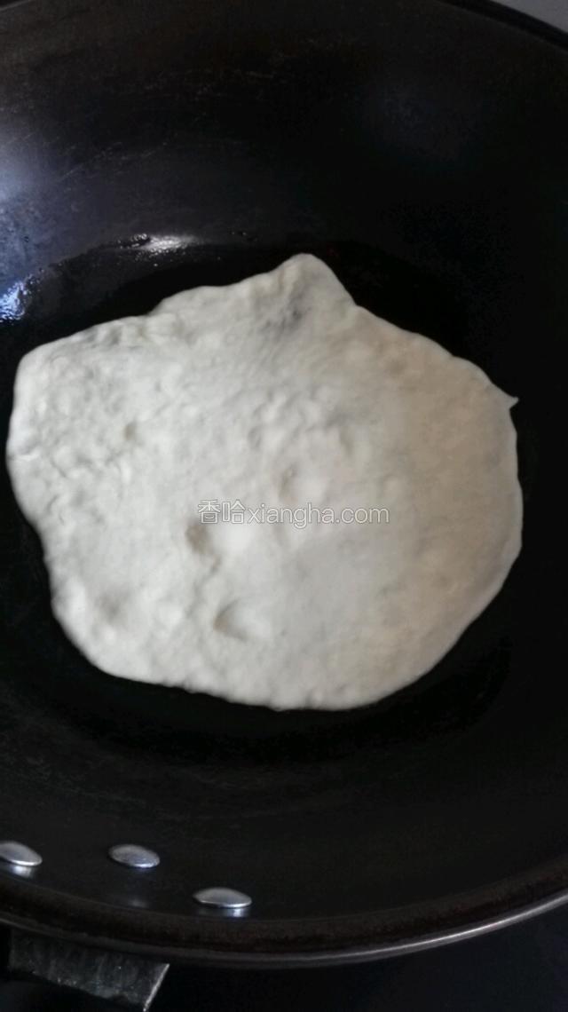 平底锅倒入底油，中小火开始烙饼，下面的饼底部别太焦了。