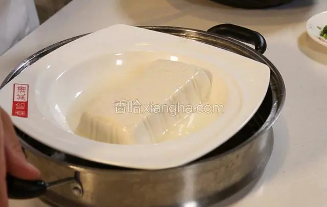 把豆腐从蒸锅取出，控去多余的水分。