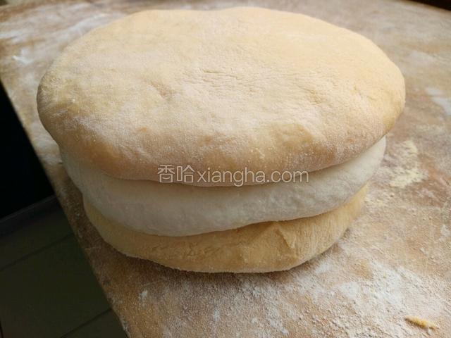 把白色面饼两面沾抹一层清水，分别在其上下各放一个胡萝卜面饼，按压均匀，使其紧密结合