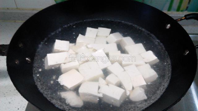 豆腐切块，大小由自己定，但要均匀。放入烧开的水中焯水，放少许的食盐一起，可去掉胆水味。焯好控水，备用。