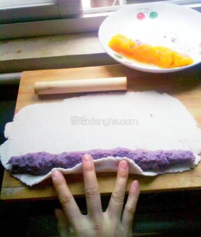馅料的话随你自己喜欢的来弄吧，我这里的是紫薯泥和豆沙还有南瓜泥！扯出一小团擀成薄薄的一片，把先前准备好的紫薯泥放在边上，从边上开始卷起！

