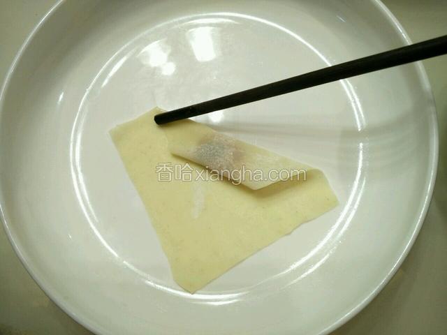 用筷子的一头沾点水，湿筷子往馄饨皮上点两下(筷子指着的位置)。