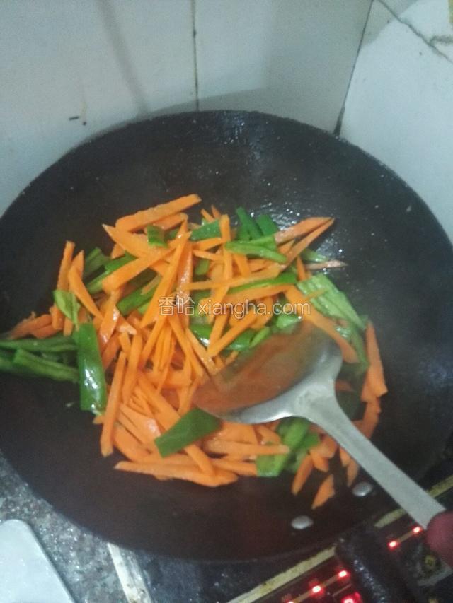 用另外干净的锅，下油烧热，加入红萝卜，翻炒一分钟，加入绿青椒炒至七分熟