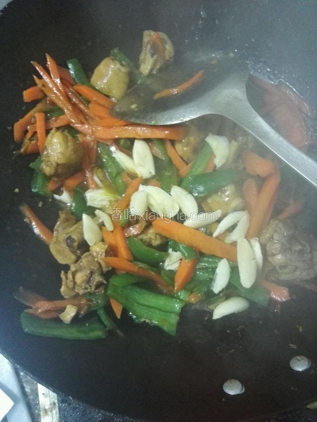 加入鸡腿，蒜瓣，盐，鸡粉调味，翻炒三分钟