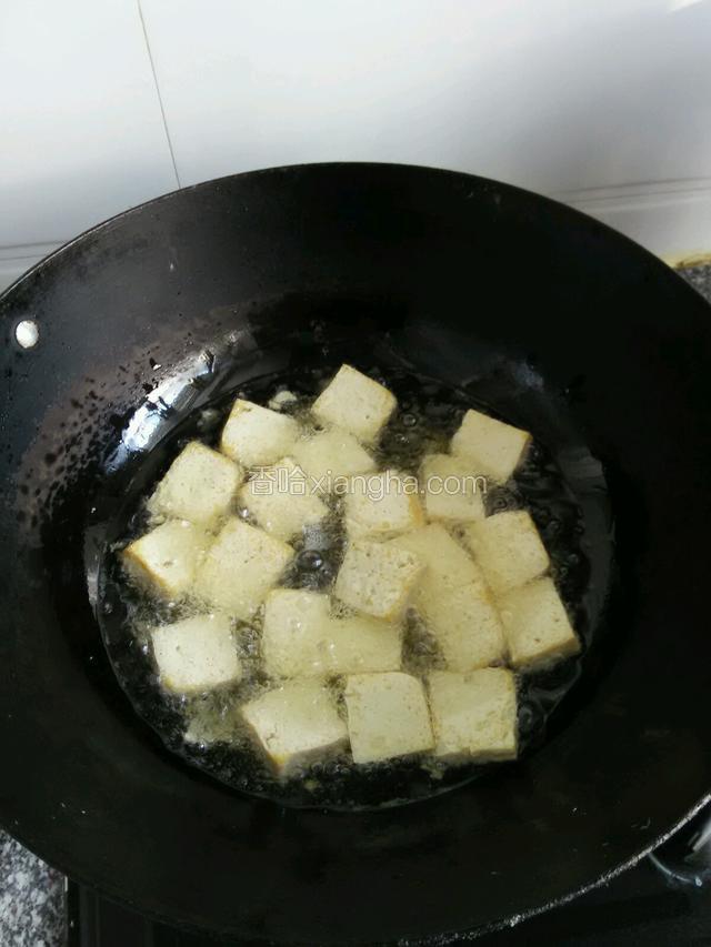 油热了后把切好的豆腐一块一块的放下去，炸上一会后要翻一面不然会粘锅炸制两面泛黄就可以了