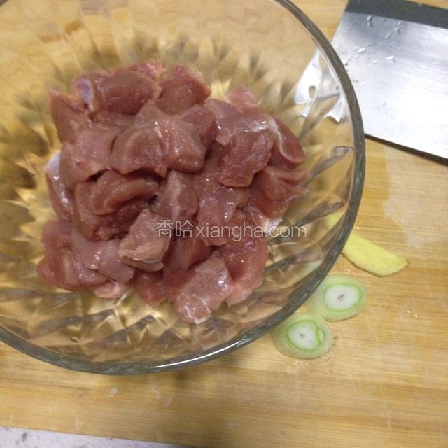 里脊肉切成1厘米左右的肉块，倒入碗中，葱切两小片，姜切一片