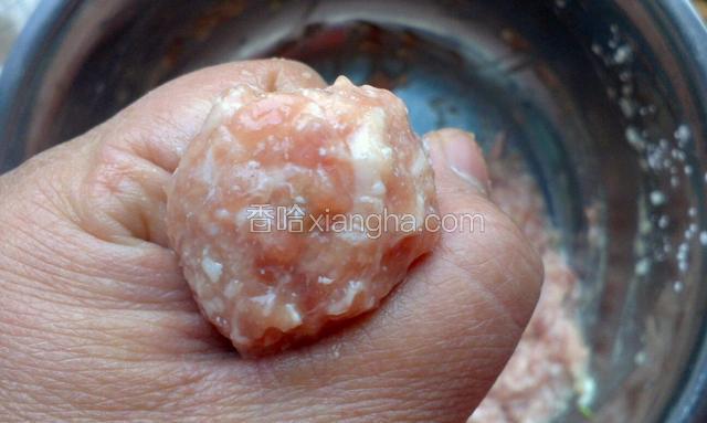 用手虎口挤出小肉丸，用小勺舀到烧开的锅里