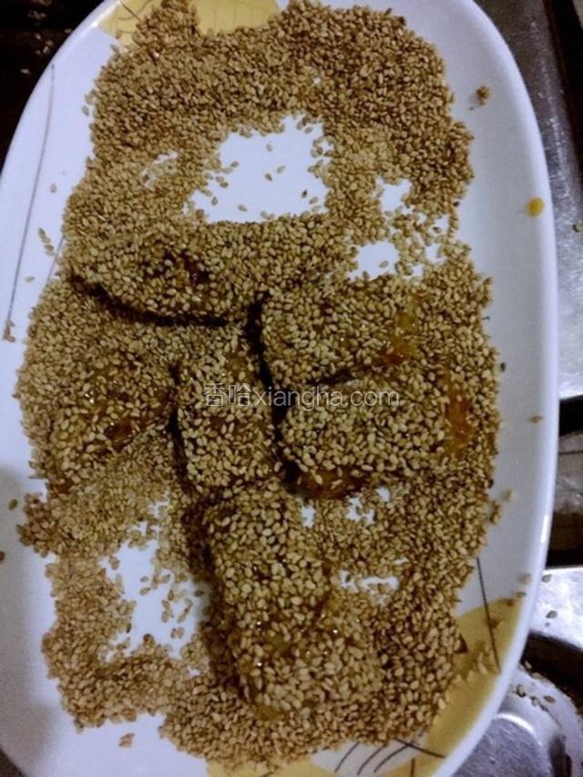 裹好糖的芋头趁热马上放到装芝麻的碗里去滚几滚，让芋头粘满芝麻