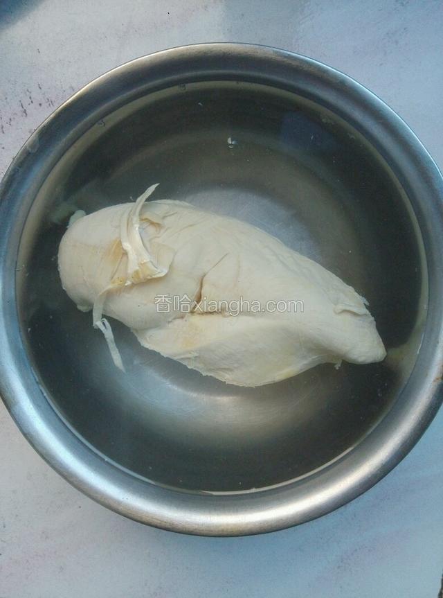 将煮好的鸡脯肉捞出后，放入之前烧好的凉白开中浸泡至凉。（煮鸡肉的汤可以留一小碗起来，不要全部倒掉，因为汤汁接下来有用处！）