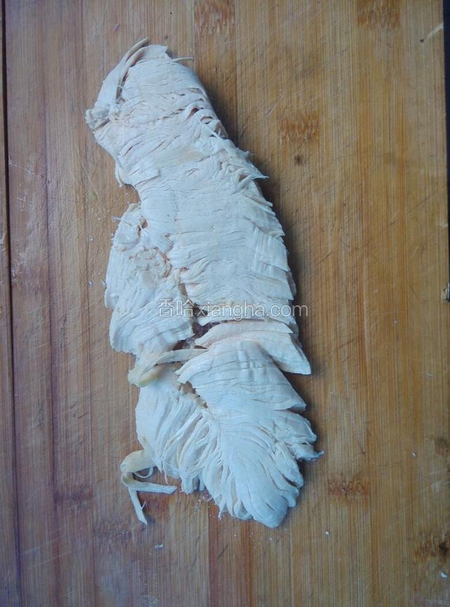 注：（浸泡过凉水的肉口感会更好）
将浸泡过凉的鸡肉放在菜板上，用擀面杖将鸡肉拍扁拍散（我家没有擀面杖，所以我用刀代替的，非常好用！）然后再用手把松软的鸡肉撕成鸡丝。