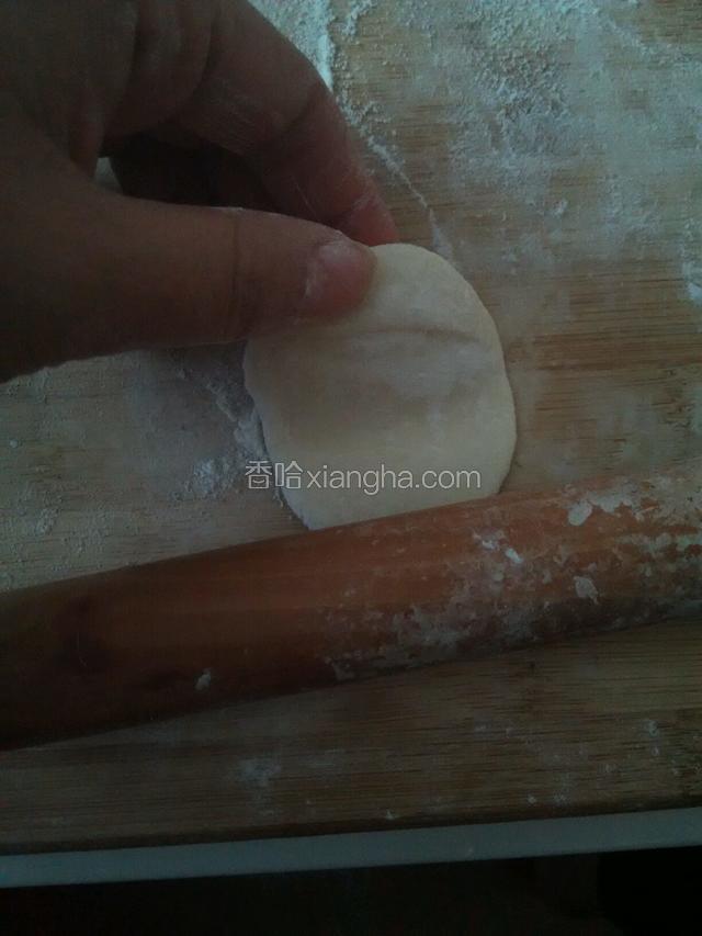 用擀面杖擀皮，一只手捏着上面部分，一点一点的向中间擀