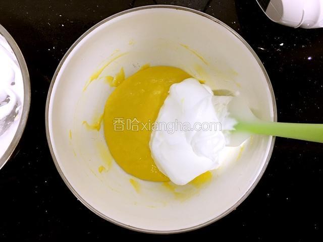 把两铲蛋白霜放入蛋黄糊中。翻拌均匀。