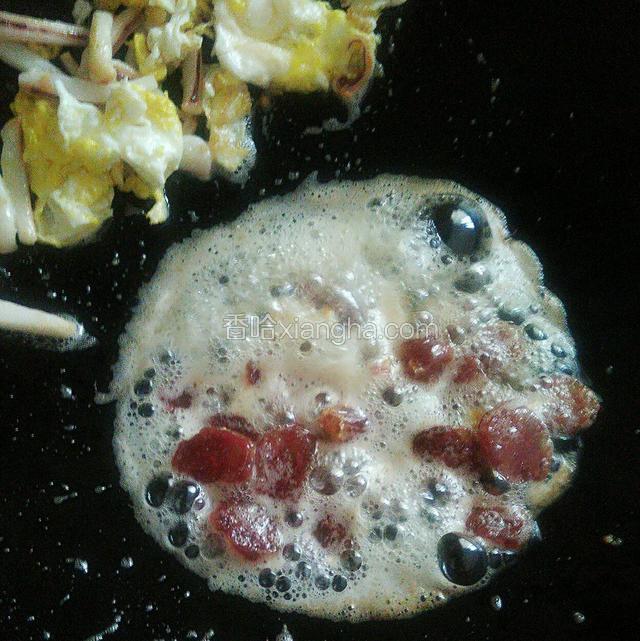 接着把熟鱿鱼和鸡蛋一起放一边，下腊肠炒熟（会有点泡沫没关系的）