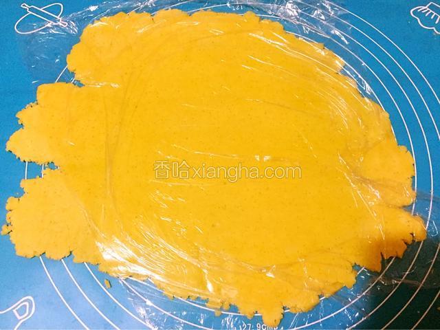 取出面团，面团上盖保鲜膜擀成一块硬币的厚度，面皮一定要擀成薄厚一致，否则烤熟的程度不一样