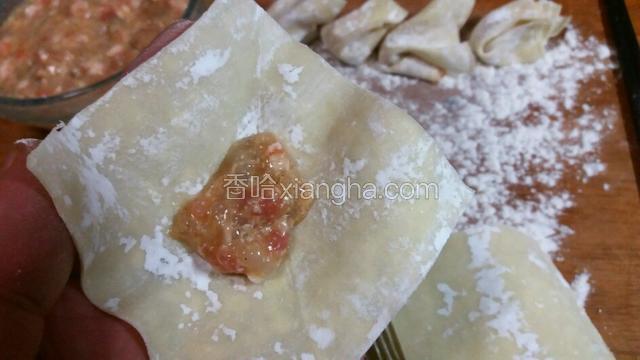 馄饨皮摊在手中，放适量的馅料。