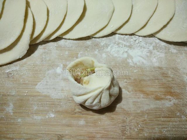 包馅了，左手托起面片，右手用勺取适量肉馅放面皮中间，再用右手拇指和食指分放面皮内外侧，均匀捏褶