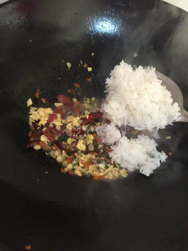用铲子将煲仔里的白饭铲到锅里。