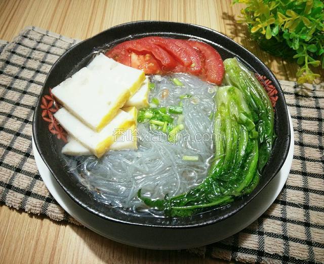 关火，捞起码入粉丝上，再码上切片的西红杮，淋入煮粉原汤，撒上葱花，即成
