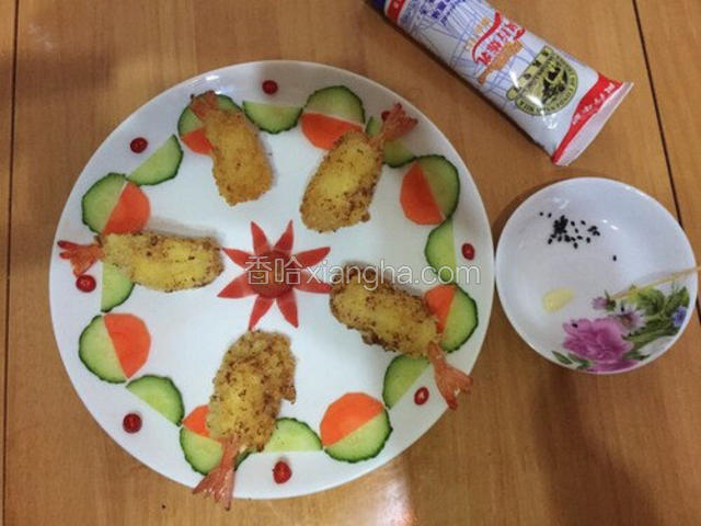 炸好的虾放入盘中，用炼奶和黑芝麻点上眼睛。