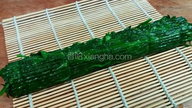 用手挤出菠菜多余的水份，用寿司帘卷成方形。