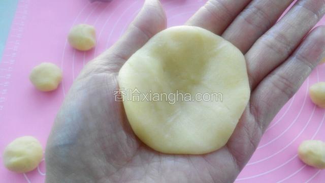 取一个面团用手掌按成饼皮。