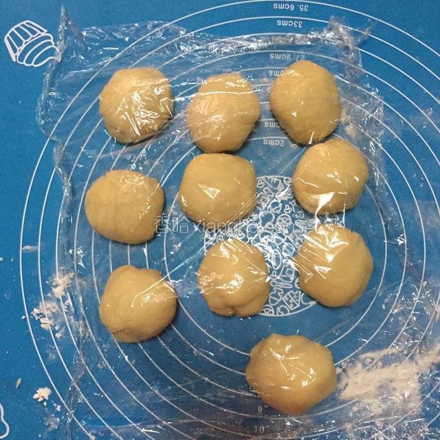 把面团分成等量大小，之后排气，滚圆。盖保鲜膜醒发15分钟左右后摆在铺油纸的烤盘上