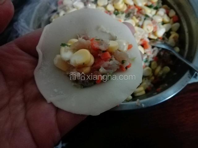 最好先拿个碗准备一点水，取一块饺子皮，放入肉馅，然后再回周围摸上一点水