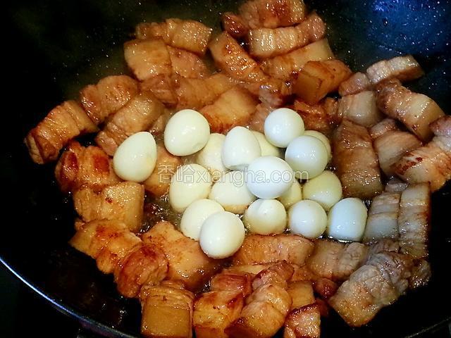 每块肉都裹上糖色后，拨到锅边，将鹌鹑蛋放入翻炒