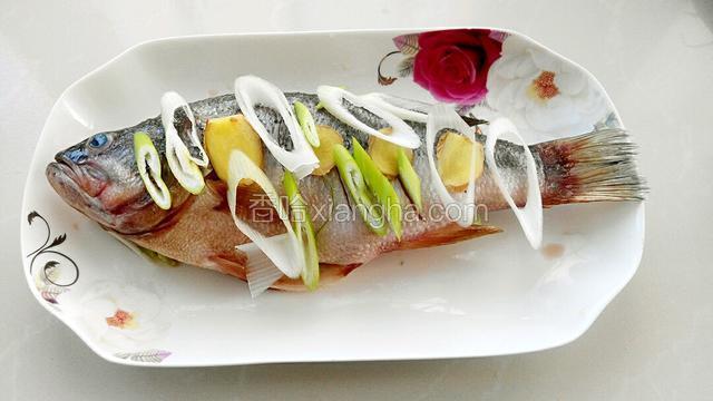 把料酒和盐混合后均匀的涂抹在鱼身上，盘底放一些姜片和葱花，然后放鱼，在鱼的身上放葱花和姜片。