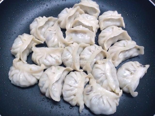 水份收干，饺子底部已煎成金黄，拿起锅晃动一下，让饺子分离。