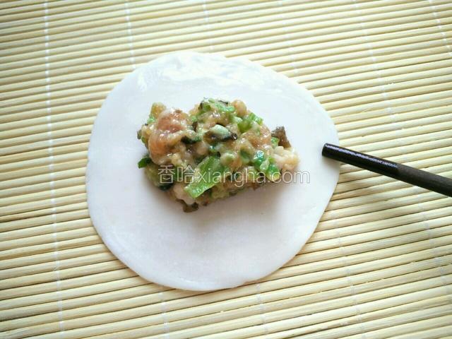 馅放入饺子皮中间，用筷子沾少许水，点湿饺子皮边缘(半圆)。