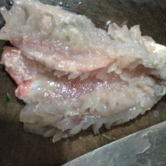 在鱼肉上切十字花刀，深至接近鱼皮，注意不要把鱼皮划破，用清水冲洗表面的黏液，沥干水分，再往鱼肉上撒少许盐和料酒腌制10分钟。