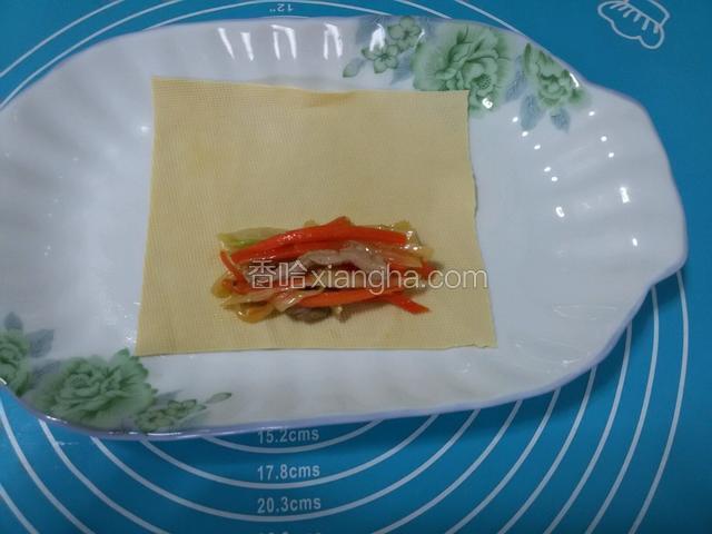 取一张豆皮，在豆皮上放入炒好的菜料